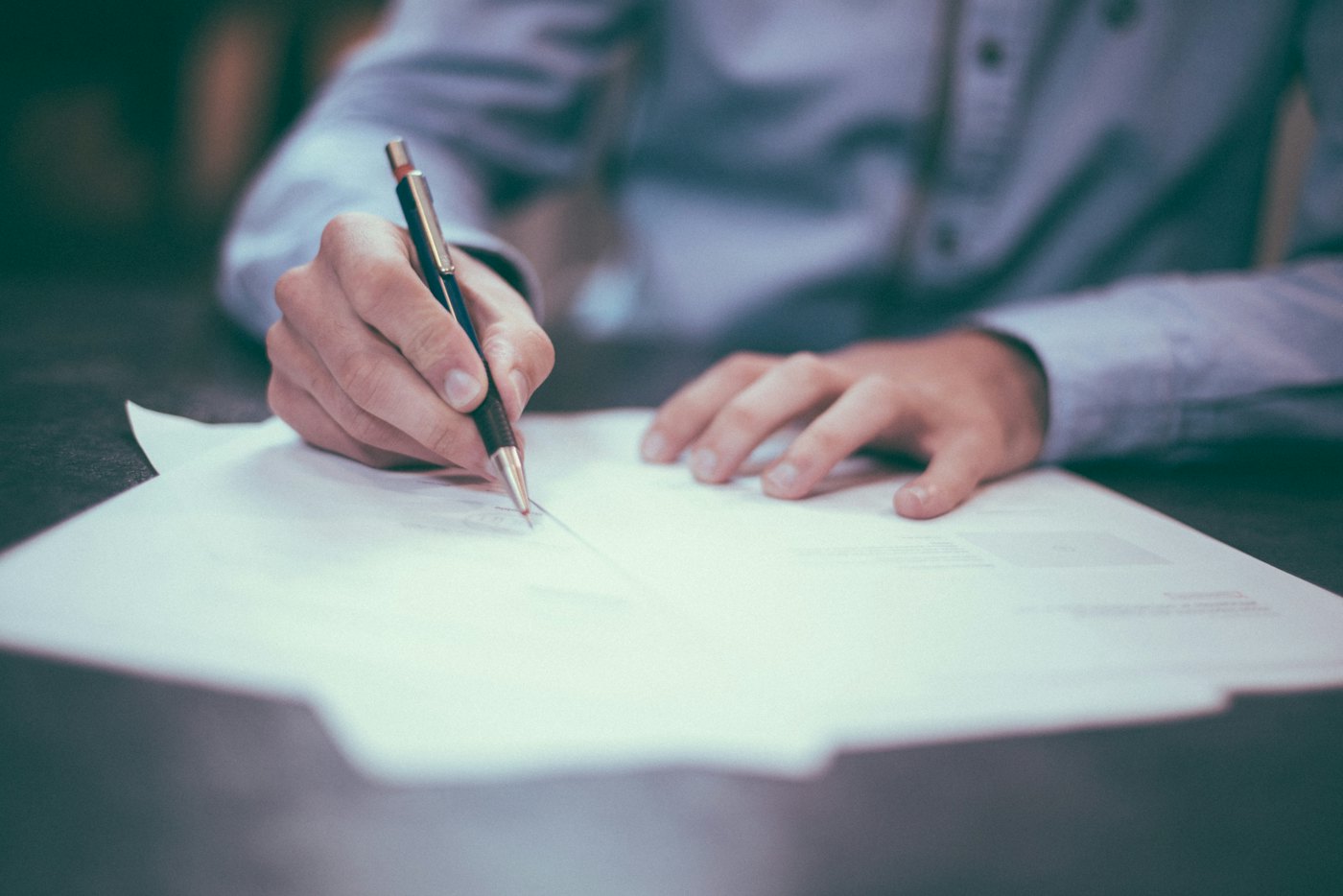 Person filling out paperwork with a pen