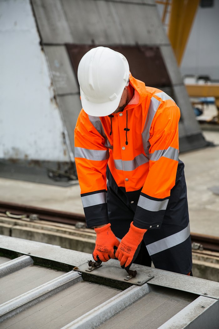 Worker in a safety jacket working on metal rails
