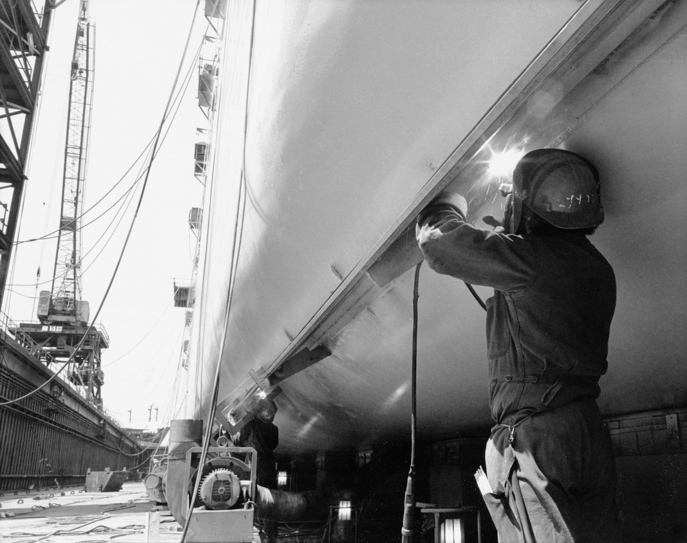Welder working on a ship hull in a dry dock